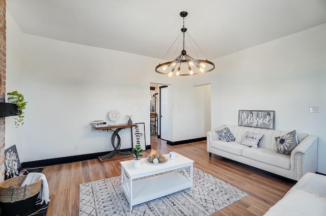 living area with a chandelier, baseboards, and wood finished floors