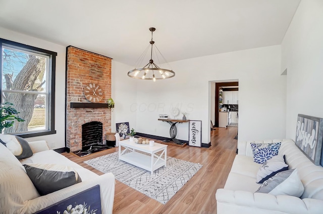 living room featuring a fireplace, a notable chandelier, and wood finished floors