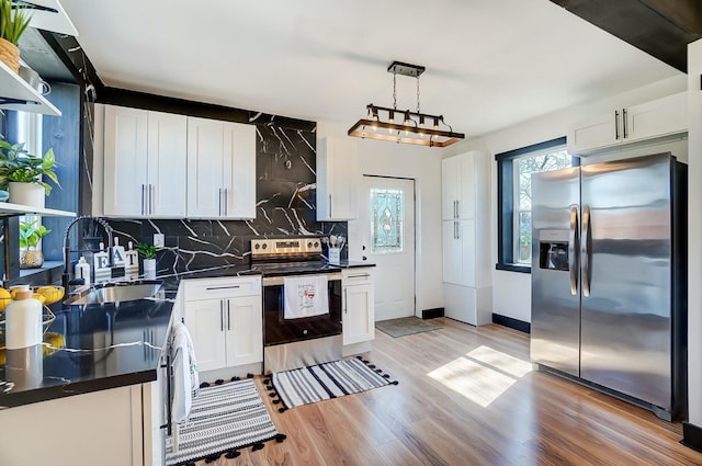 kitchen featuring dark countertops, light wood-style floors, appliances with stainless steel finishes, and a sink