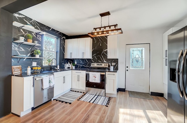 kitchen featuring light wood-style flooring, a sink, backsplash, dark countertops, and appliances with stainless steel finishes