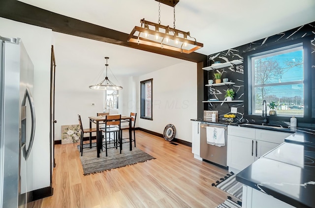 kitchen with white cabinetry, light wood-style flooring, a sink, and stainless steel appliances