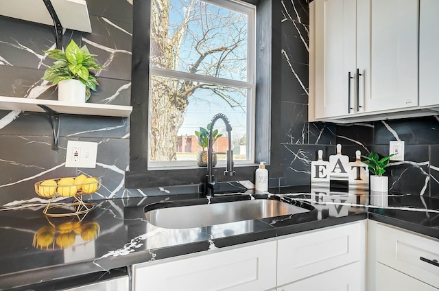 kitchen featuring dark countertops, decorative backsplash, white cabinetry, and a sink