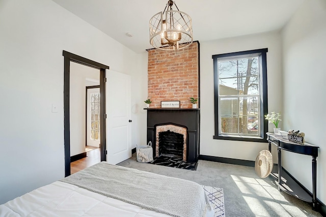 bedroom featuring carpet flooring, an inviting chandelier, a fireplace, and baseboards