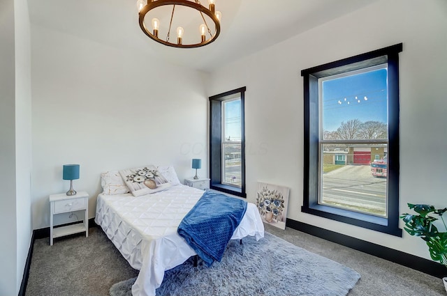 carpeted bedroom with baseboards and a chandelier