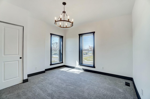 spare room with a notable chandelier, visible vents, baseboards, and carpet floors