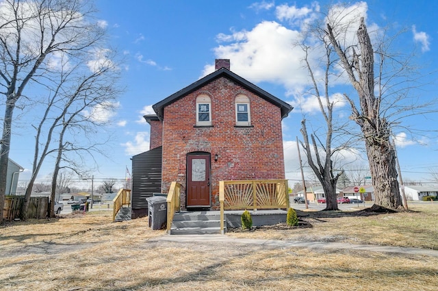 view of front facade featuring brick siding and a chimney