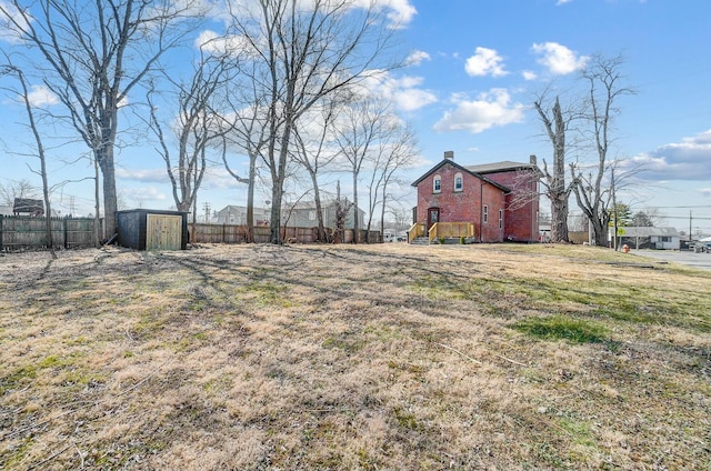 view of yard featuring a storage shed, an outbuilding, and fence