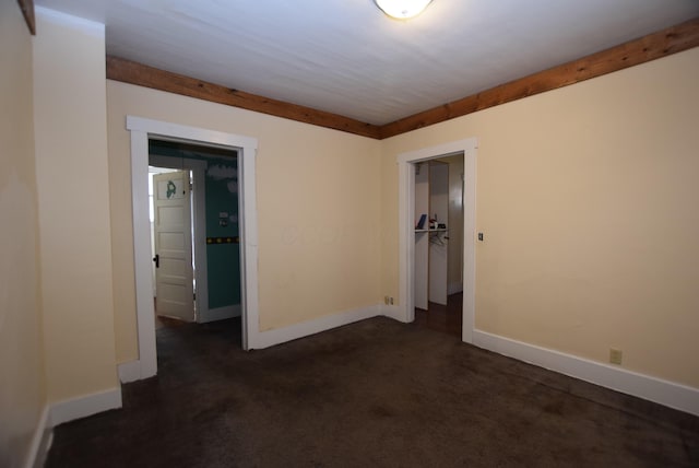 empty room with baseboards and dark colored carpet