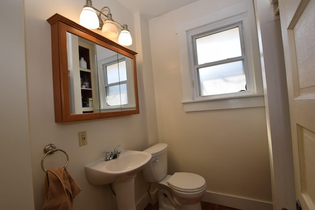 bathroom with toilet, baseboards, and a sink