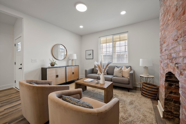 living room with a brick fireplace, recessed lighting, wood finished floors, and baseboards