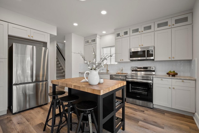 kitchen featuring decorative backsplash, wood finished floors, appliances with stainless steel finishes, and butcher block counters