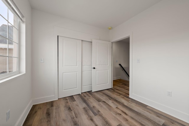 unfurnished bedroom featuring a closet, baseboards, and wood finished floors