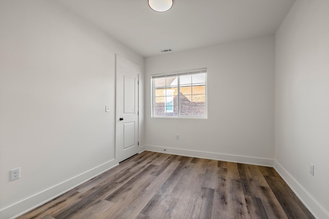 unfurnished room with visible vents, baseboards, and wood finished floors