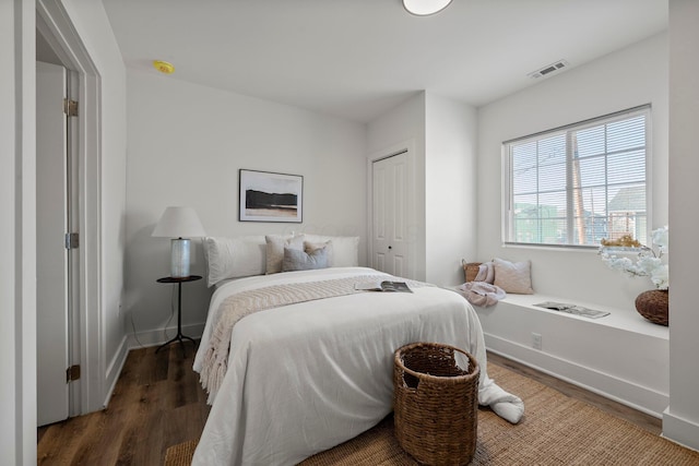 bedroom with a closet, visible vents, baseboards, and wood finished floors