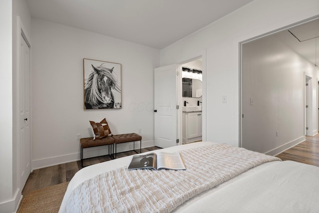 bedroom with baseboards, attic access, and wood finished floors