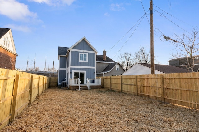 back of house featuring central air condition unit, board and batten siding, and a fenced backyard