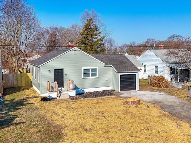 rear view of property with fence, driveway, a yard, a shingled roof, and a garage