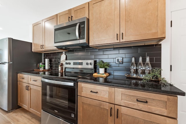 kitchen featuring dark stone countertops, backsplash, appliances with stainless steel finishes, and light brown cabinets