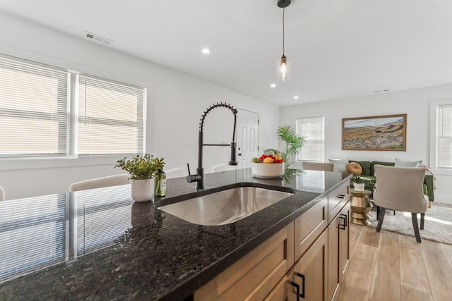 kitchen with visible vents, recessed lighting, a sink, hanging light fixtures, and light wood-style floors