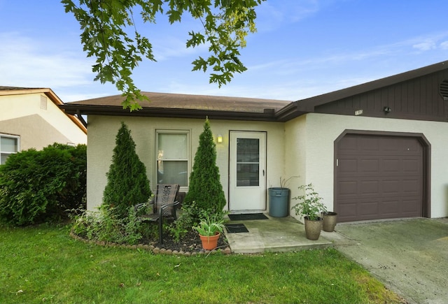 view of front of home featuring a garage, concrete driveway, a front lawn, and stucco siding