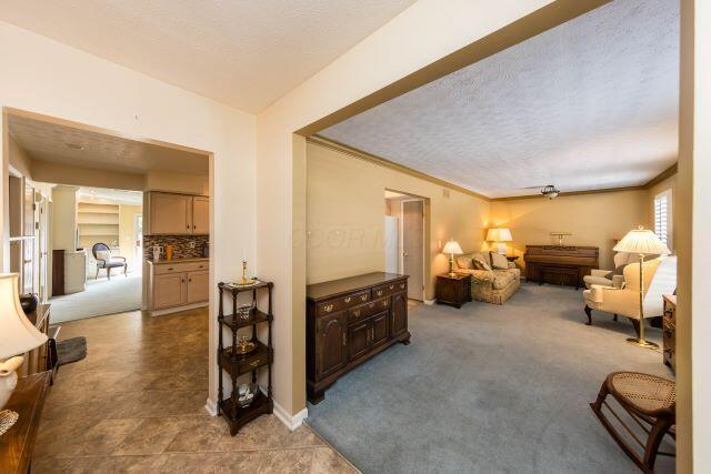 interior space with light carpet, ornamental molding, and a textured ceiling