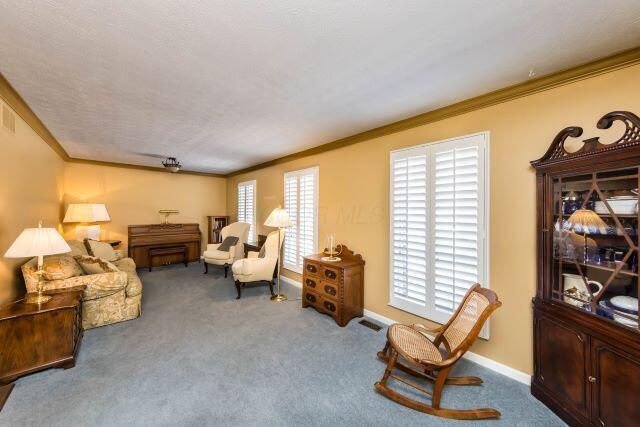 sitting room with plenty of natural light, crown molding, and carpet