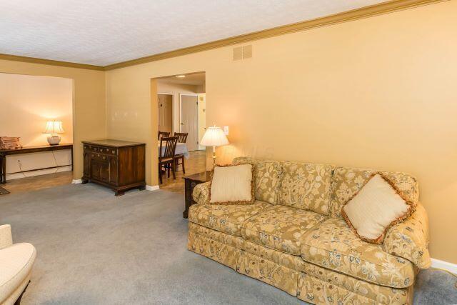 living room with visible vents, ornamental molding, baseboards, and carpet floors