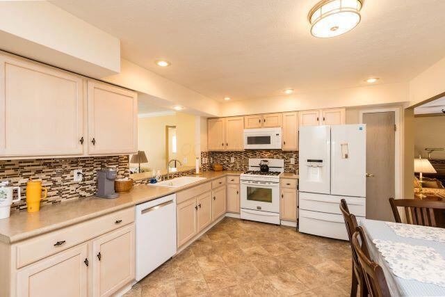 kitchen with tasteful backsplash, light countertops, recessed lighting, white appliances, and a sink