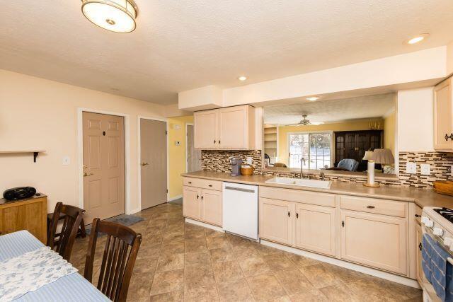 kitchen featuring white appliances, light countertops, backsplash, and a sink