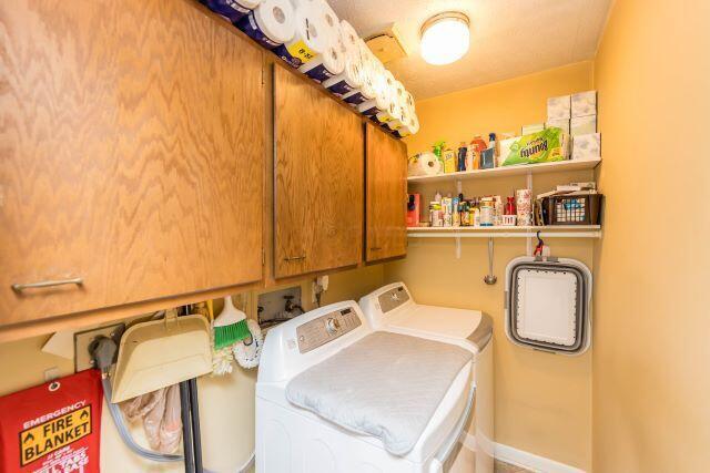 clothes washing area featuring washer and dryer and cabinet space