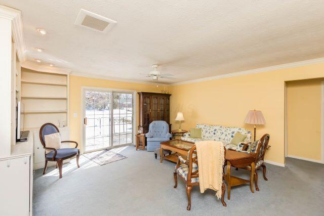 interior space featuring carpet flooring, crown molding, and a ceiling fan