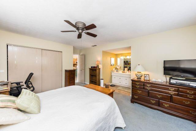 carpeted bedroom featuring visible vents, a ceiling fan, a closet, and connected bathroom