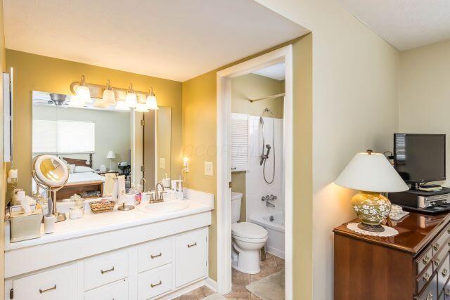 bathroom featuring toilet, vanity, and shower / tub combination