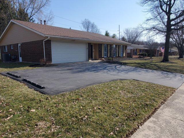 ranch-style home featuring brick siding, a front lawn, central AC, a garage, and driveway