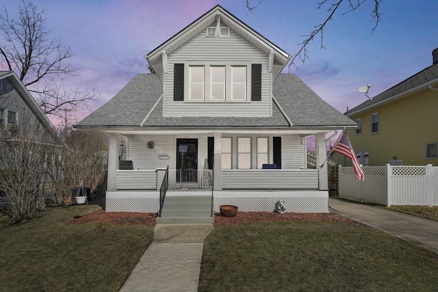 view of front of property featuring a porch, a front yard, roof with shingles, and fence