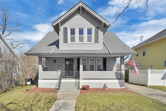 bungalow-style house featuring covered porch, fence, a front lawn, and roof with shingles