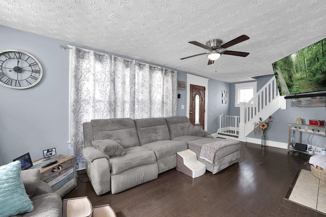 living area with a textured ceiling, wood finished floors, baseboards, ceiling fan, and stairs