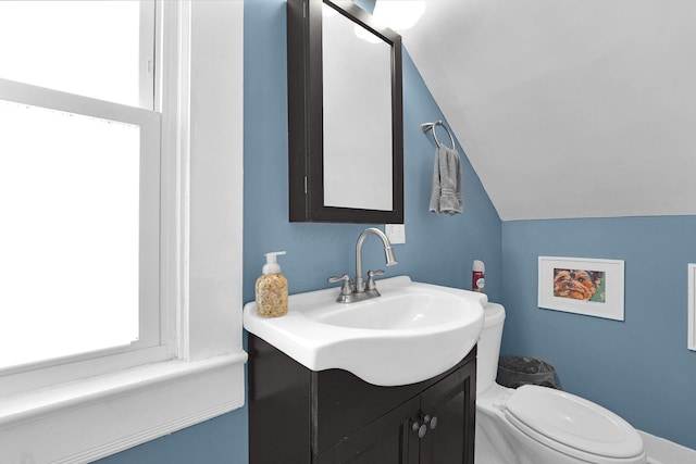 bathroom with toilet, vanity, and lofted ceiling