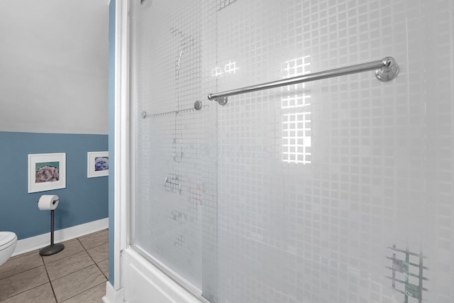 full bathroom featuring baseboards, toilet, lofted ceiling, tile patterned floors, and a shower