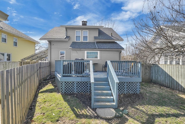 rear view of property featuring a wooden deck, a yard, a fenced backyard, and a chimney