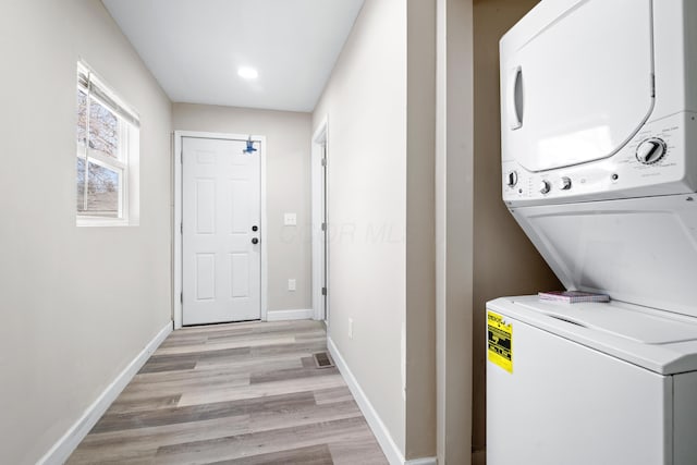 laundry area with baseboards, visible vents, laundry area, light wood-style flooring, and stacked washer / drying machine