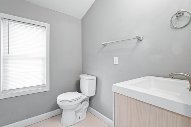 half bathroom featuring toilet, vanity, and baseboards