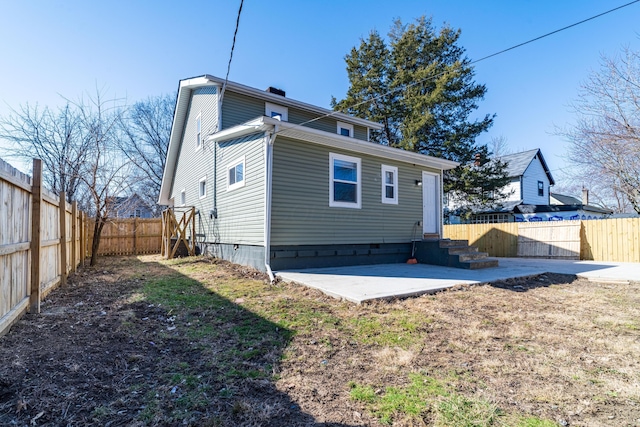 rear view of house featuring entry steps, a patio, and a fenced backyard