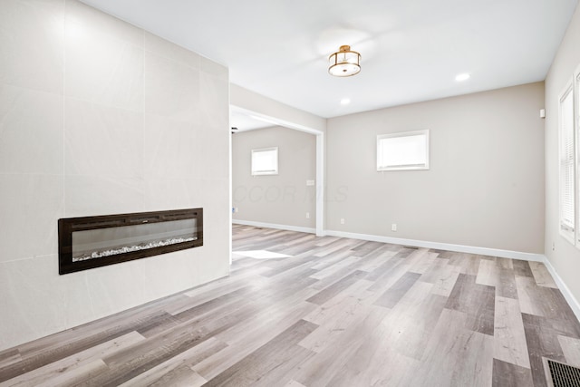 basement with visible vents, baseboards, a fireplace, and light wood finished floors