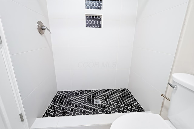 full bathroom with tiled shower and toilet