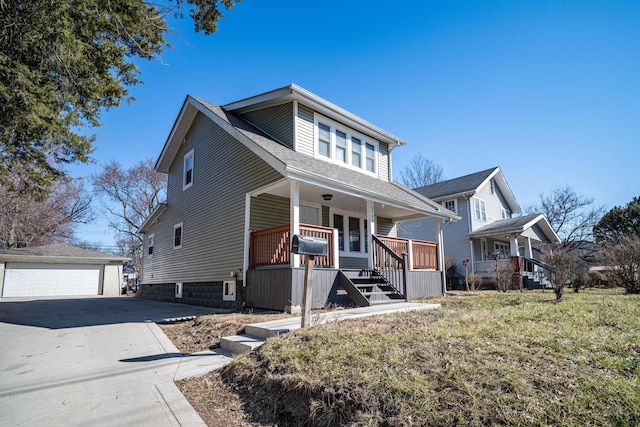 view of front of home featuring a shingled roof, a front yard, covered porch, a garage, and an outbuilding