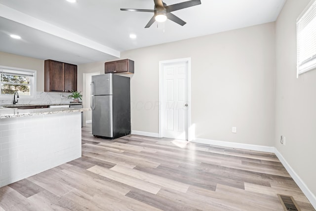 kitchen with light wood-type flooring, visible vents, freestanding refrigerator, baseboards, and dark brown cabinets