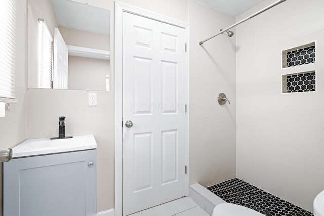 bathroom featuring toilet, tiled shower, and vanity