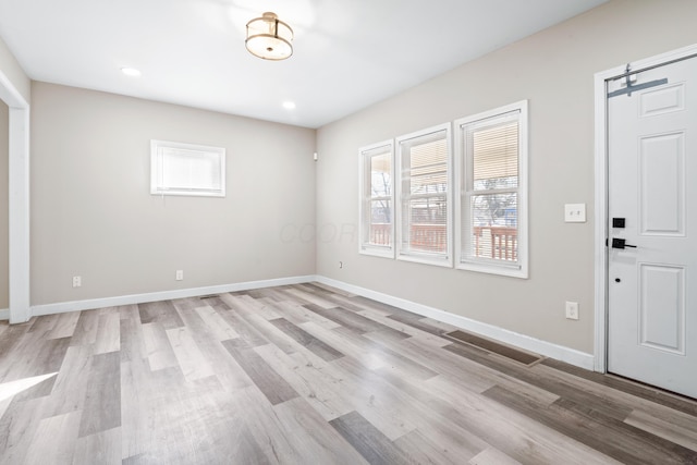 entrance foyer featuring a barn door, recessed lighting, baseboards, and light wood finished floors