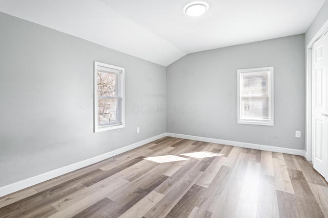 unfurnished bedroom with light wood finished floors, baseboards, and vaulted ceiling